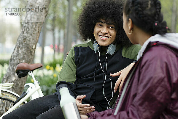 Junger Mann mit Afro im Gespräch mit einem Freund im Park