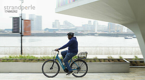 Mann fährt mit dem Fahrrad entlang der Uferpromenade der Stadt