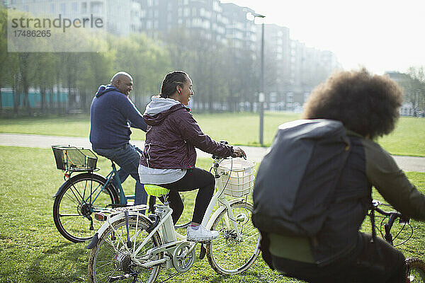 Glückliche Familie auf Fahrrädern im sonnigen Stadtpark Gras