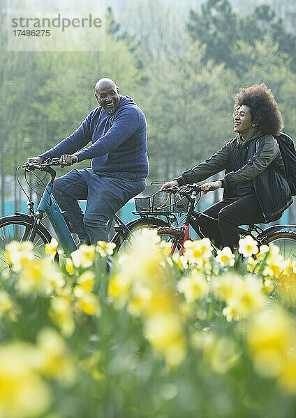 Glücklicher Vater und Teenager-Sohn beim Fahrradfahren im Frühlingspark