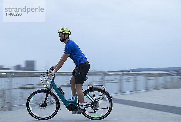 Mann fährt mit dem Fahrrad entlang der städtischen Uferpromenade