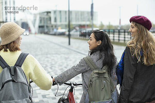 Junge Frauen Freunde mit Fahrrad auf städtischen Bürgersteig
