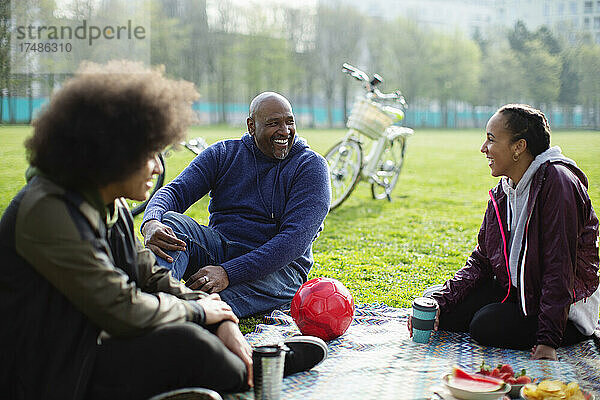 Glücklicher Vater und Teenager-Kinder genießen ein Picknick im Stadtpark