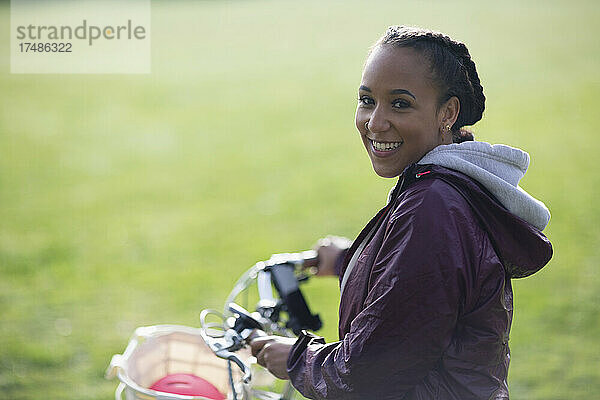 Porträt glückliche schöne junge Frau fährt Fahrrad im Park