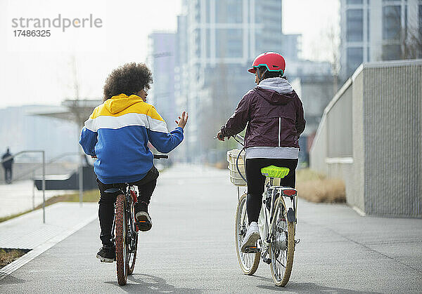 Teenager-Freunde fahren mit dem Fahrrad auf einem Radweg in der Stadt
