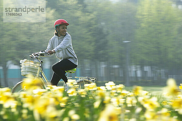 Glückliche junge Frau auf dem Fahrrad in einem sonnigen Frühlingspark