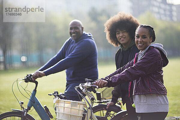Porträt glücklicher Vater und Teenager-Kinder mit Fahrrädern im Park