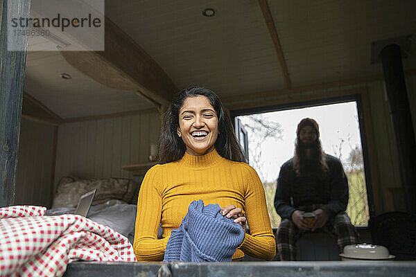Glückliche junge Frau lachend in winziger gemieteter Hütte