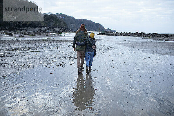 Zärtliches junges Paar  das am nassen Sandstrand spazieren geht