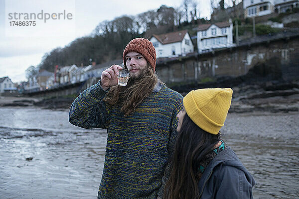 Portrait junges Paar trinkt Wein am Winterstrand