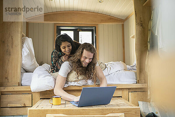 Glückliches junges Paar benutzt Laptop in kleinem Kabinenbett