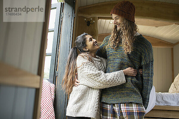 Glückliches junges Paar  das sich in einer kleinen gemieteten Hütte umarmt