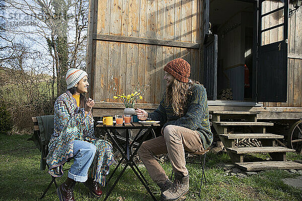 Glückliches junges Paar beim Essen vor einer kleinen gemieteten Hütte