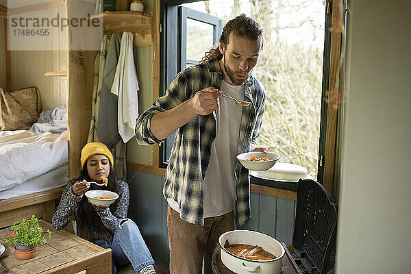 Junges Paar kocht in einer winzigen gemieteten Hütte