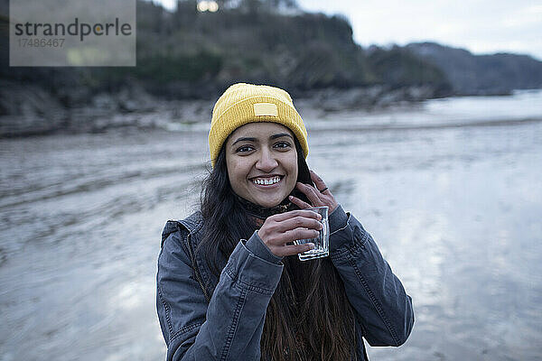 Porträt glückliche junge Frau trinkt am Strand