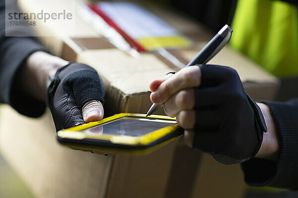 Close up Kurier mit Smartphone und Stift bei der Auslieferung eines Pakets