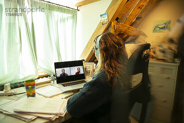 Frau hält Videokonferenz mit Kollegen auf dem Laptop-Bildschirm zu Hause