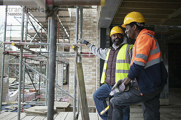 Männliche Bauarbeiter unterhalten sich auf der Baustelle