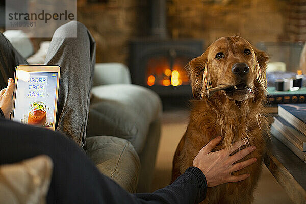 Mann mit Hund  der über ein digitales Tablet einen Imbiss bestellt