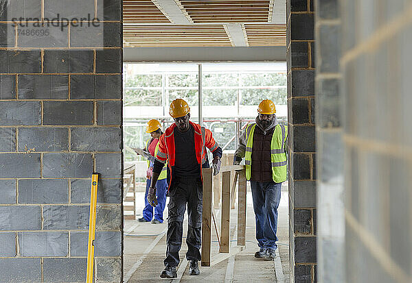 Bauarbeiter tragen Holzrahmen auf der Baustelle