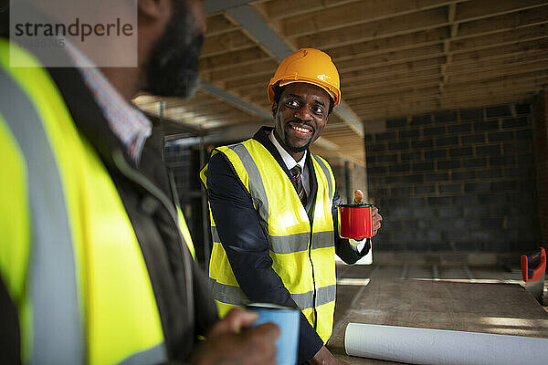 Männliche Architekten trinken Kaffee auf der Baustelle