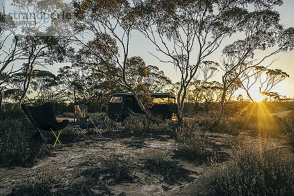 Campingstühle und geparkter Van im australischen Busch bei Sonnenuntergang