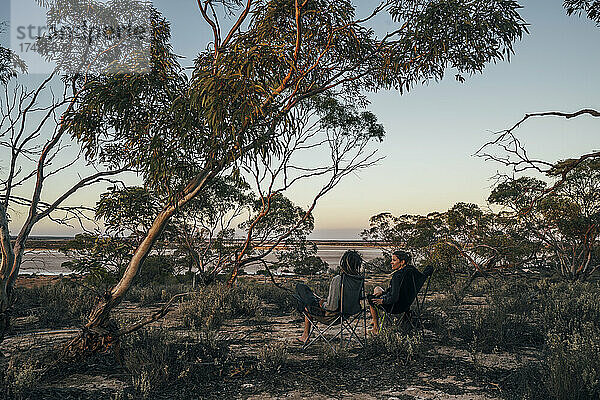 Ehepaar entspannt sich in Campingstühlen unter Bäumen  Australien