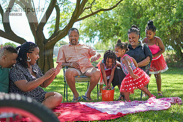 Mehrgenerationen-Familie beim Wasserspritzen im Sommerpark