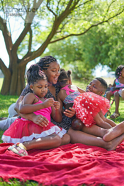 Glückliche Familie entspannt sich auf einer Decke im Sommerpark
