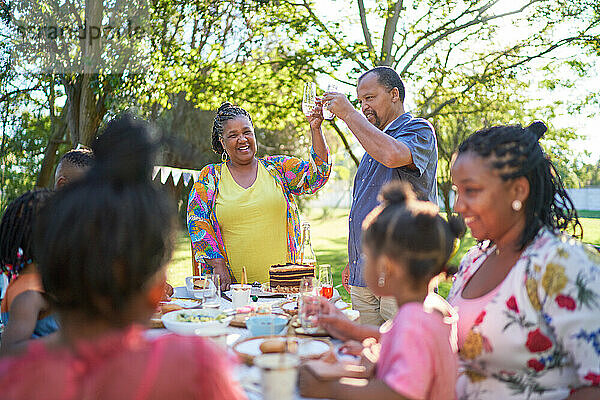 Glückliche Mehrgenerationen-Familie feiert Geburtstag im sommerlichen Hinterhof