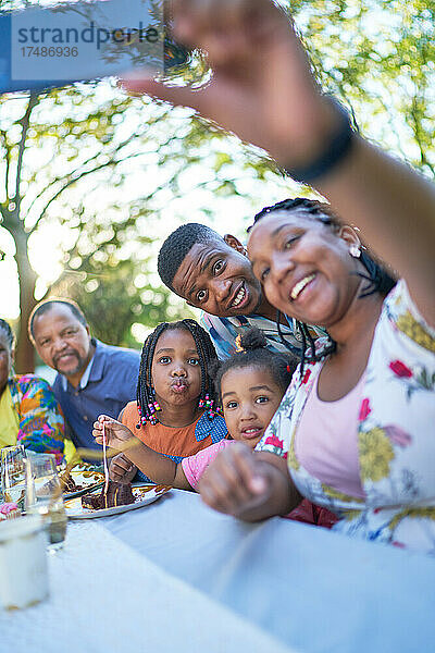 Mehrgenerationenfamilie macht Selfie am Terrassentisch
