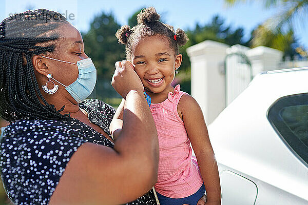 Porträt Mutter hilft süßes Kleinkind Tochter mit Gesichtsmaske