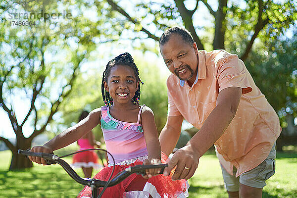 Porträt glücklicher Großvater und Enkelin beim Fahrradfahren im Park