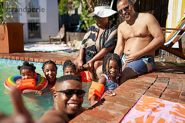 Porträt einer glücklichen Mehrgenerationenfamilie am sonnigen Sommerschwimmbad