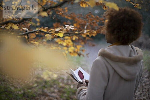 Junge Frau mit Tagebuch in ruhigem Herbstpark