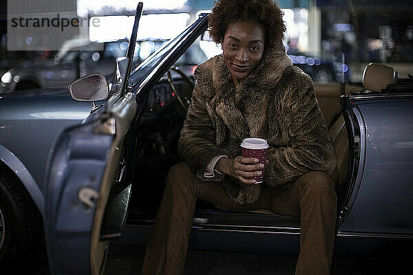 Porträt selbstbewusste junge Frau mit Kaffee im Cabrio