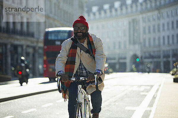 Glücklicher Geschäftsmann auf dem Fahrrad in einer sonnigen Straße  London  UK