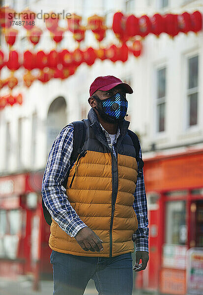 Männlicher Tourist mit Gesichtsmaske beim Spaziergang in der Stadt