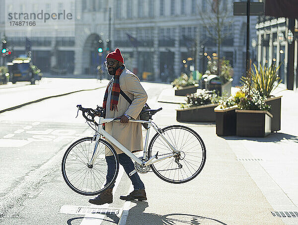 Geschäftsmann mit Fahrrad auf sonniger Stadtstraße