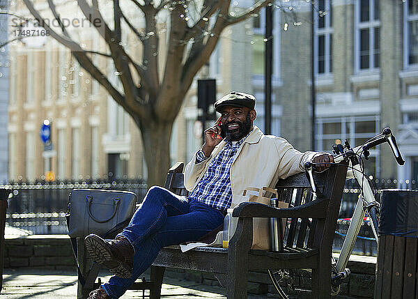 Geschäftsmann spricht auf einer Bank im Stadtpark mit seinem Smartphone