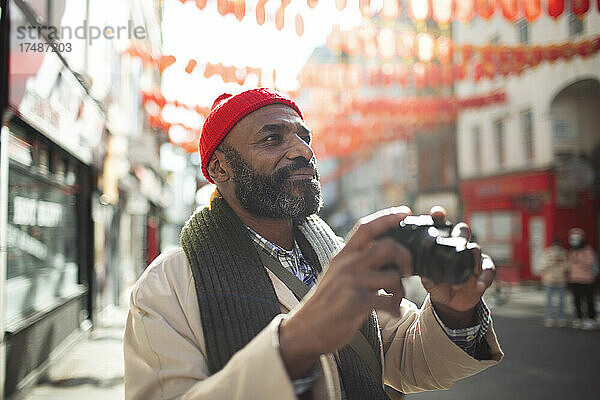 Männlicher Tourist mit Digitalkamera auf einer Stadtstraße