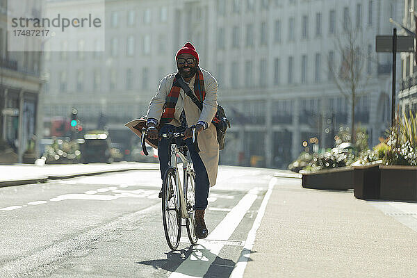 Männlicher Pendler auf dem Fahrrad auf einer sonnigen Straße in der Stadt