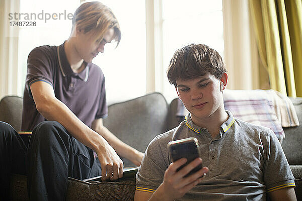 Teenager-Jungen mit Smartphone beim Lernen zu Hause