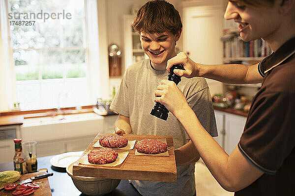 Fröhliche Teenager bereiten in der Küche Hamburger-Patties zu