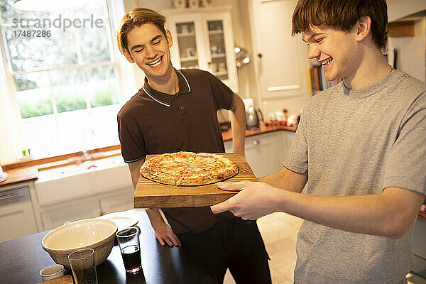 Glückliche Teenager-Jungs mit Pizza in der Küche