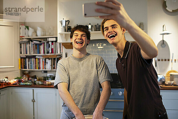 Glückliche Teenager-Jungs lachen und nehmen Selfie in der Küche