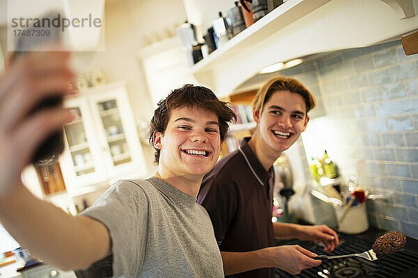 Glückliche Teenager-Jungen nehmen Selfie und Kochen in der Küche