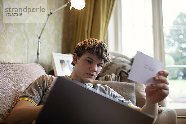 Jugendlicher mit Laptop beim Lernen im Wohnzimmer