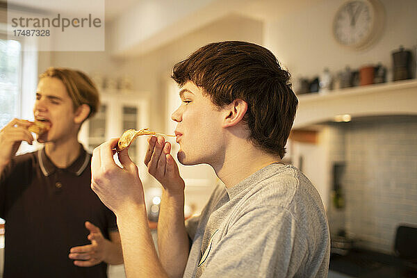 Teenager-Jungen essen Pizza in der Küche