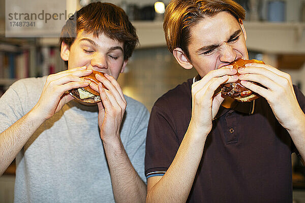 Hungrige Teenager essen Hamburger